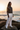 Black model — white linen pants, beach rocks golden hour