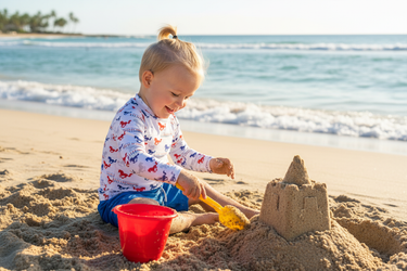 Boy at beach building sandcastle