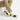 Man wearing yellow and black slip-ons with khaki chinos, ankles crossed