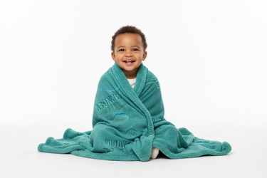 Toddler wrapped in safari blanket, smiling